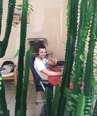 Thomas Gal mit ungefähr 18 am Schreibtisch in seinem ersten Office, hinter Kakteen